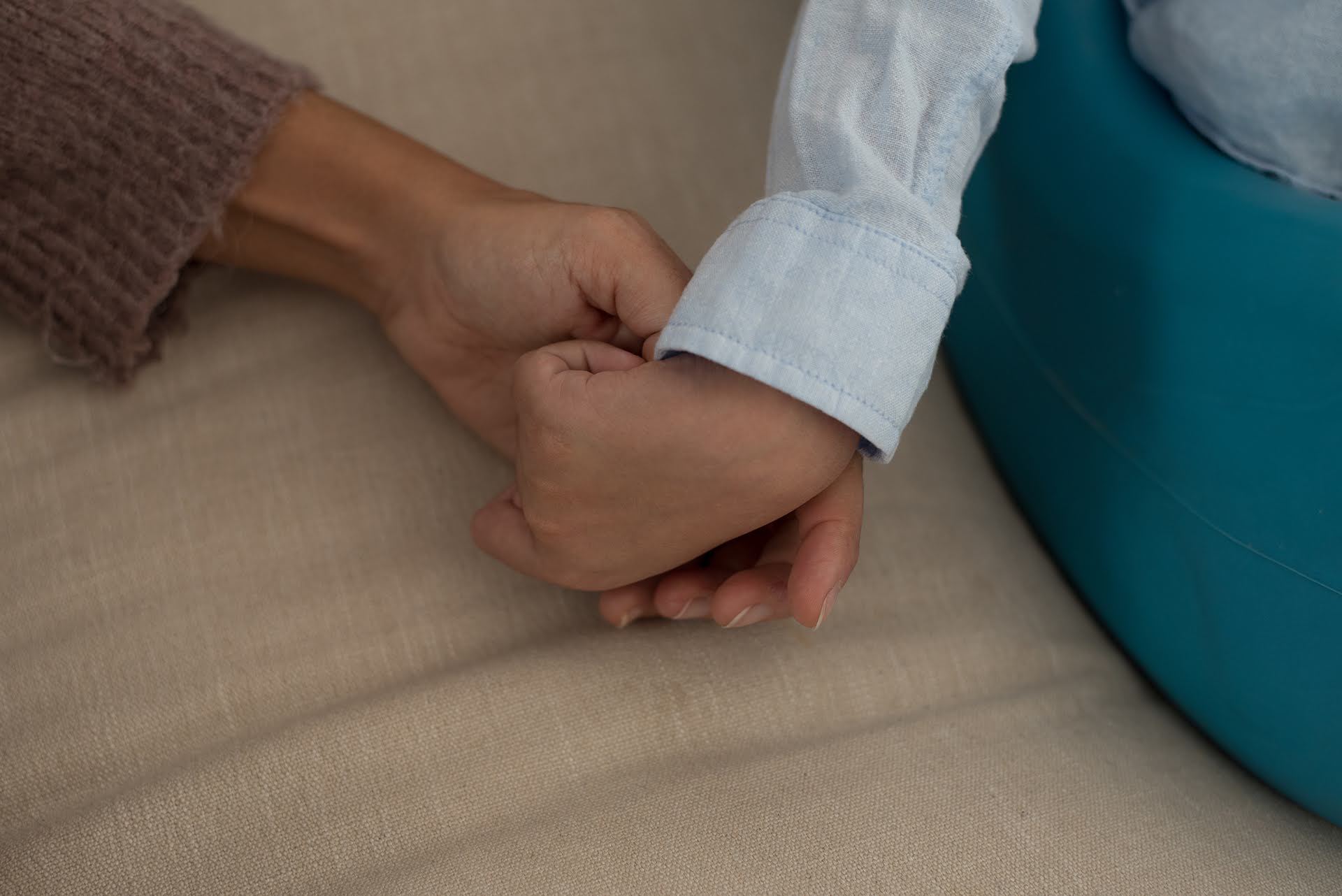 Un adulto de la Fundación porqueViven sostiene con ternura la mano de un niño en cuidado paliativo pediátrico en Madrid