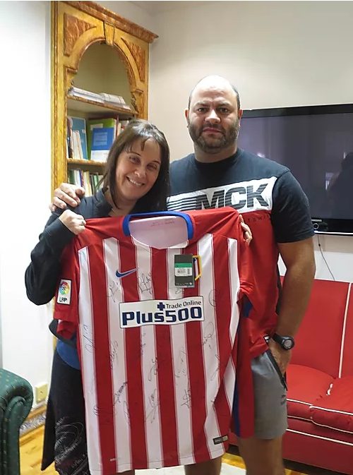 En Madrid, una mujer y un hombre muestran una camiseta firmada junto a material Fundación porqueViven, compartiendo ilusión