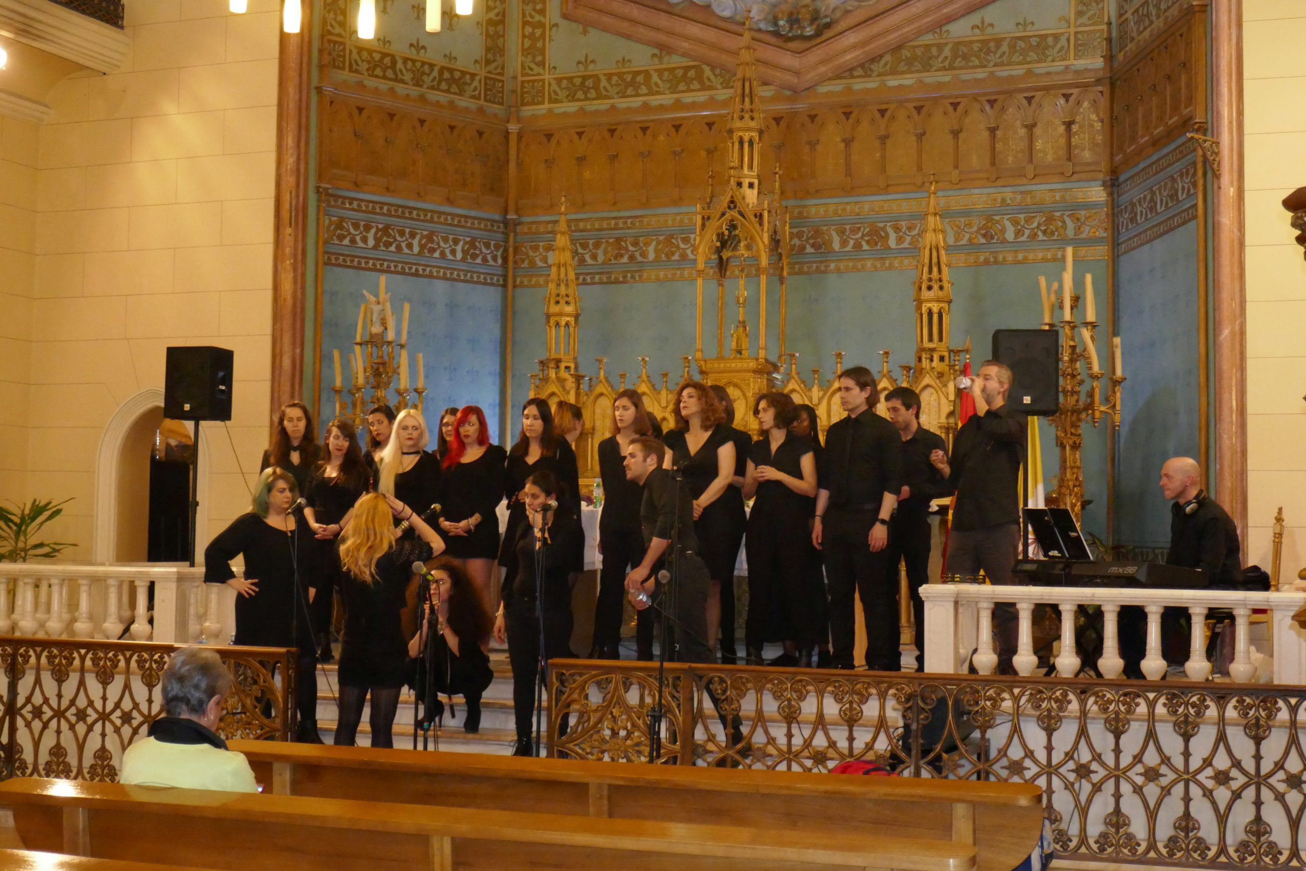 Un coro de unas quince personas canta en una iglesia decorada con oro, en un evento