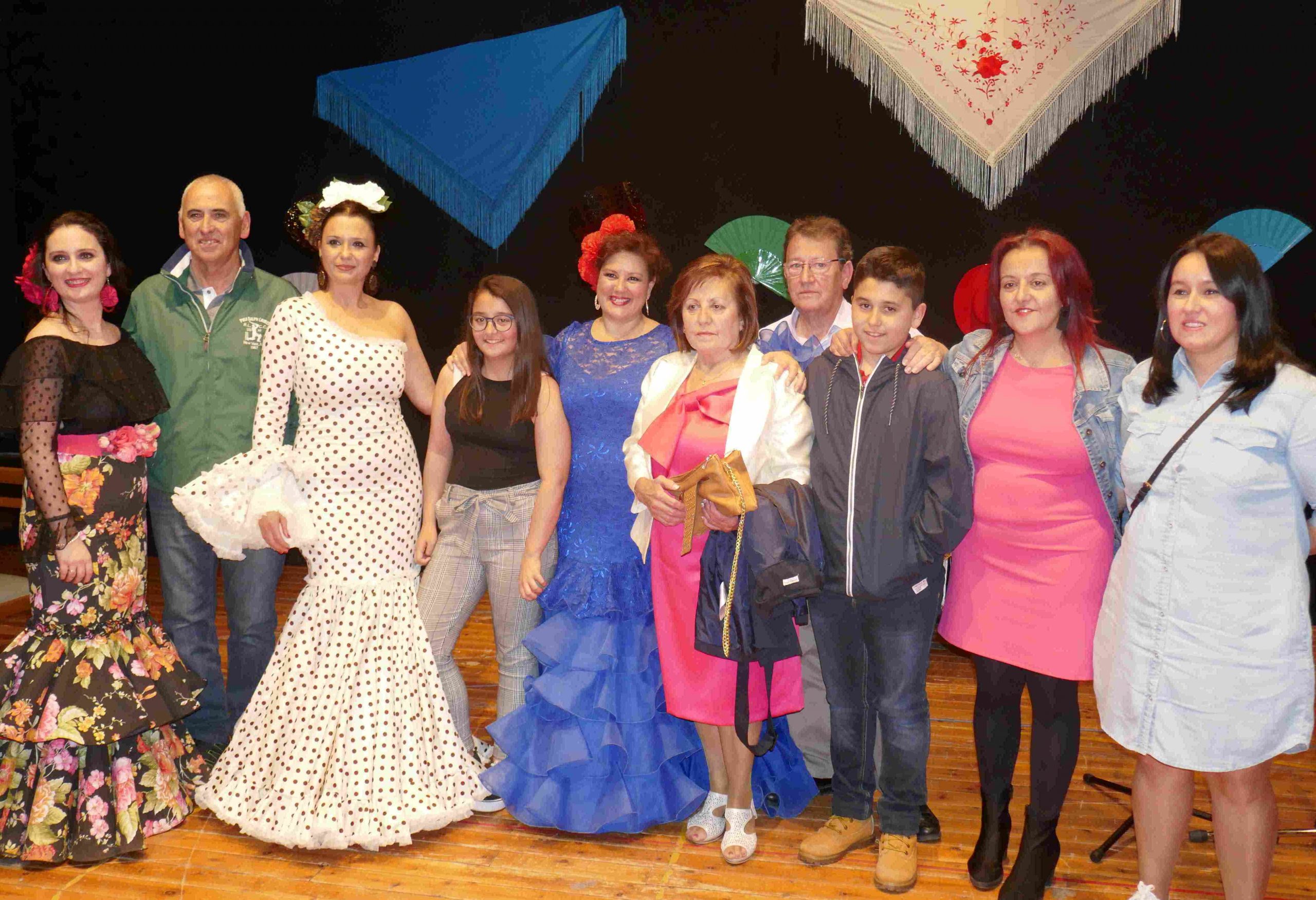 Integrantes posan sonrientes en el escenario, algunas con trajes flamencos, celebrando la vida