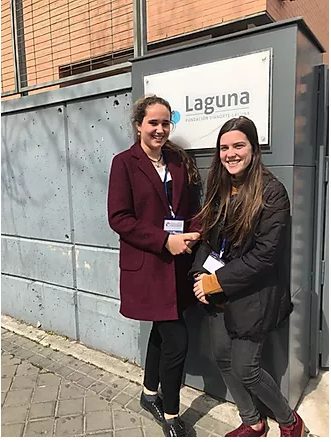 Dos profesionales Fundación porqueViven sonríen junto al cartel de Laguna, mostrando su compromiso