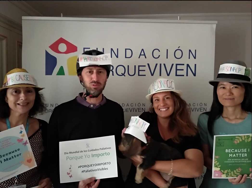Cuatro personas sonríen frente al cartel Fundación porqueViven, mostrando mensajes solidarios a favor
