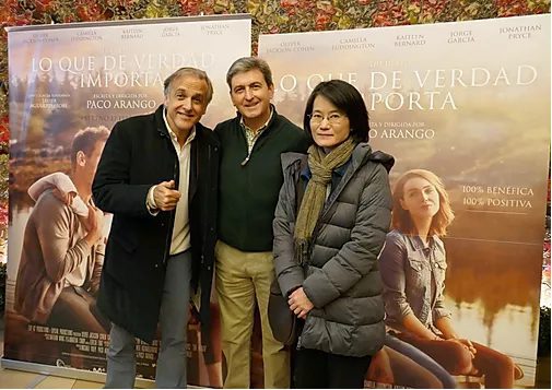 Tres adultos del equipo Fundación porqueViven sonríen juntos ante carteles de "Lo Que de Verdad Importa" en Madrid