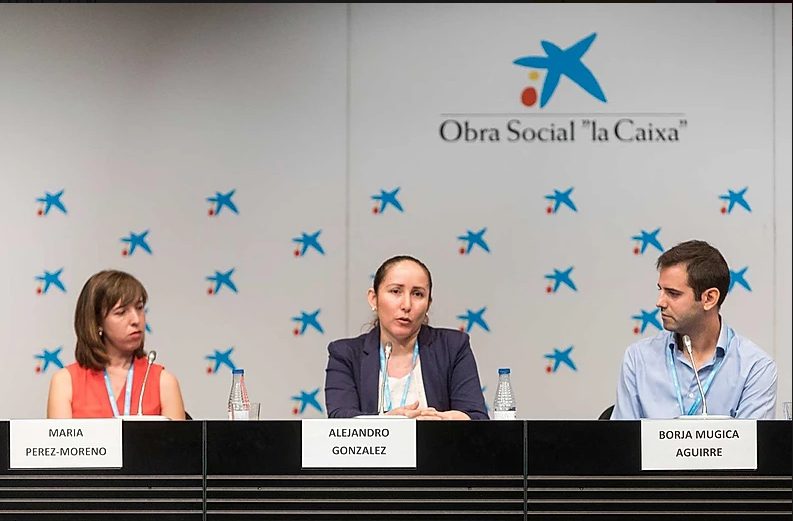 En una mesa redonda sobre , representantes Fundación porqueViven y expertos como Maria Perez-Moreno, Alejandro Gonzalez y Borja Mugica Aguirre comparten experiencias. Al fondo, el logo de Obra Social la Caixa refuerza el compromiso social del evento