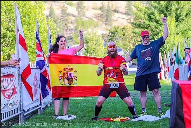 En la meta, tres personas con la bandera de España celebran juntos, mostrando el espíritu
