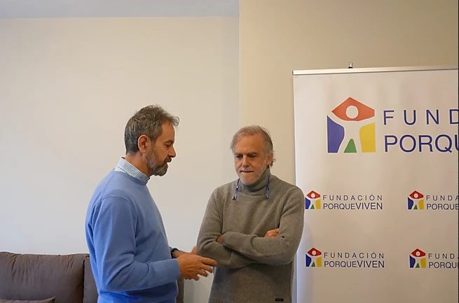 Dos profesionales conversan junto al cartel Fundación porqueViven, dedicados