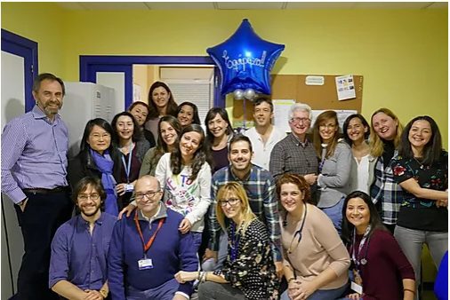 Equipo Fundación porqueViven sonríe reunido en su oficina en Madrid, celebrando el compromiso con los cuidados paliativos pediátricos