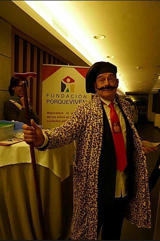 Junto a un cartel Fundación porqueViven, una persona caracterizada anima un evento