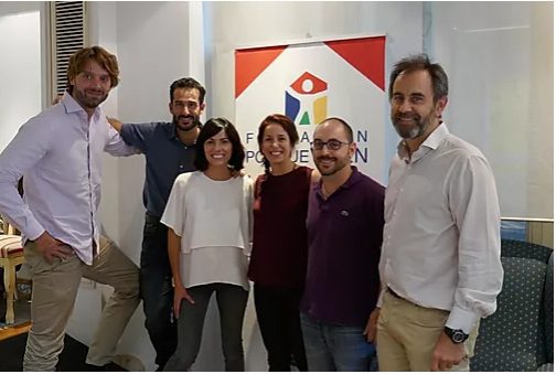 Seis personas sonrientes del equipo de cuidados paliativos pediátricos posan junto a un cartel