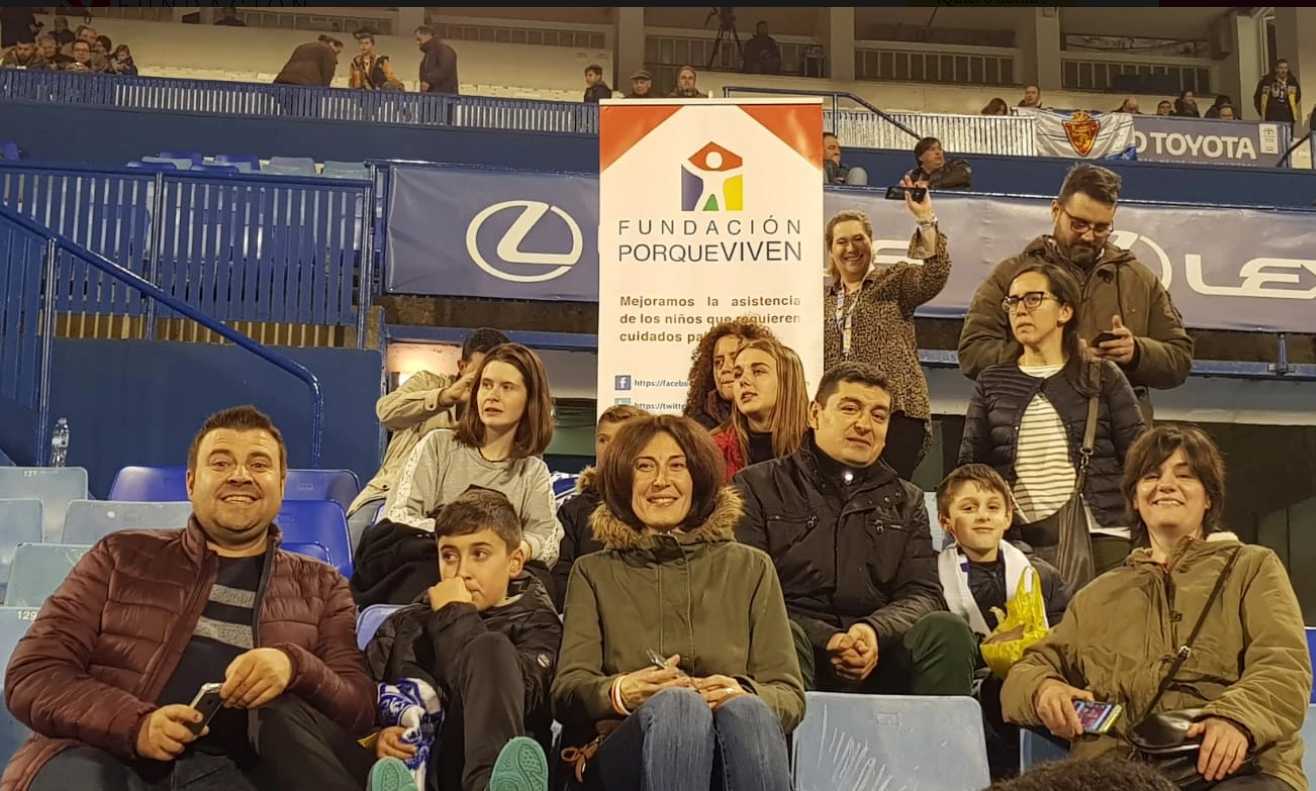 Miembros Fundación porqueViven sonríen juntos en gradas azules, mostrando unión y apoyo en cuidados paliativos pediátricos