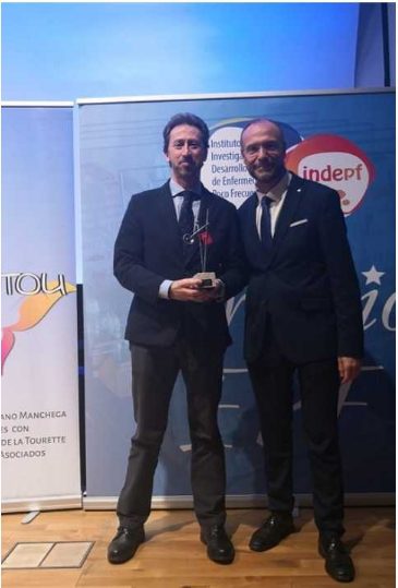 Dos profesionales en traje posan juntos, uno sostiene un galardón Fundación porqueViven en un evento sobre
