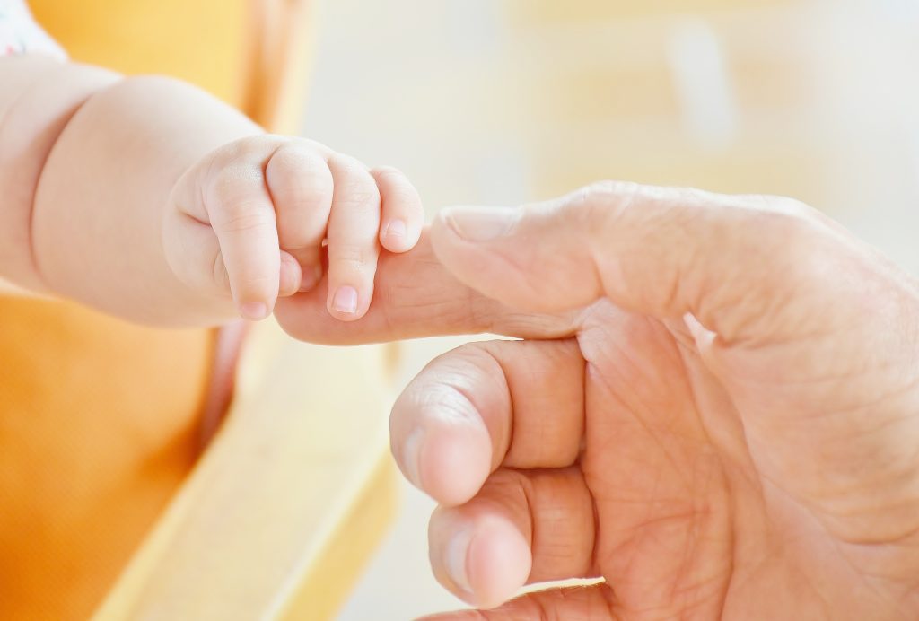 La mano de un bebé aferrada al dedo de un adulto simboliza el cuidado y apoyo Fundación porqueViven en paliativos pediátricos