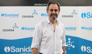 Un hombre con barba y bigote, camisa blanca de mangas remangadas, posa ante un fondo de Sanidad, Cogesa y