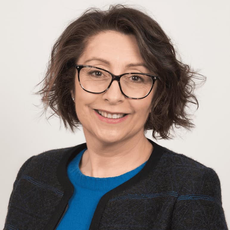 Una mujer con pelo corto y ondulado y gafas sonríe con calidez, reflejando el compromiso humano Fundación porqueViven