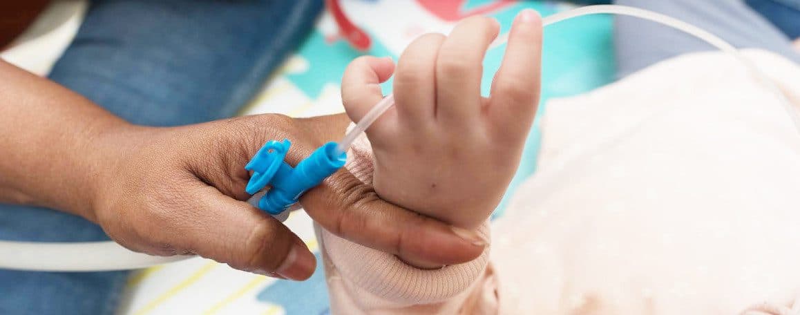Un profesional Fundación porqueViven conecta una vía a un bebé bajo