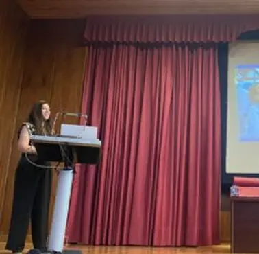 Una ponente Fundación porqueViven expone sobre paliativos pediátricos en Madrid, junto a una pantalla azul y amarilla