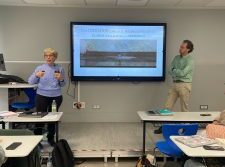 Dos profesionales presentan cuidados paliativos pediátricos en aula de Madrid, ante materiales y pantalla