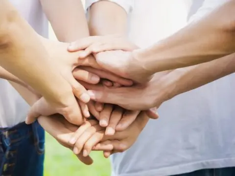 Manos de varias personas se unen en señal de trabajo en equipo y apoyo, valores clave en Madrid