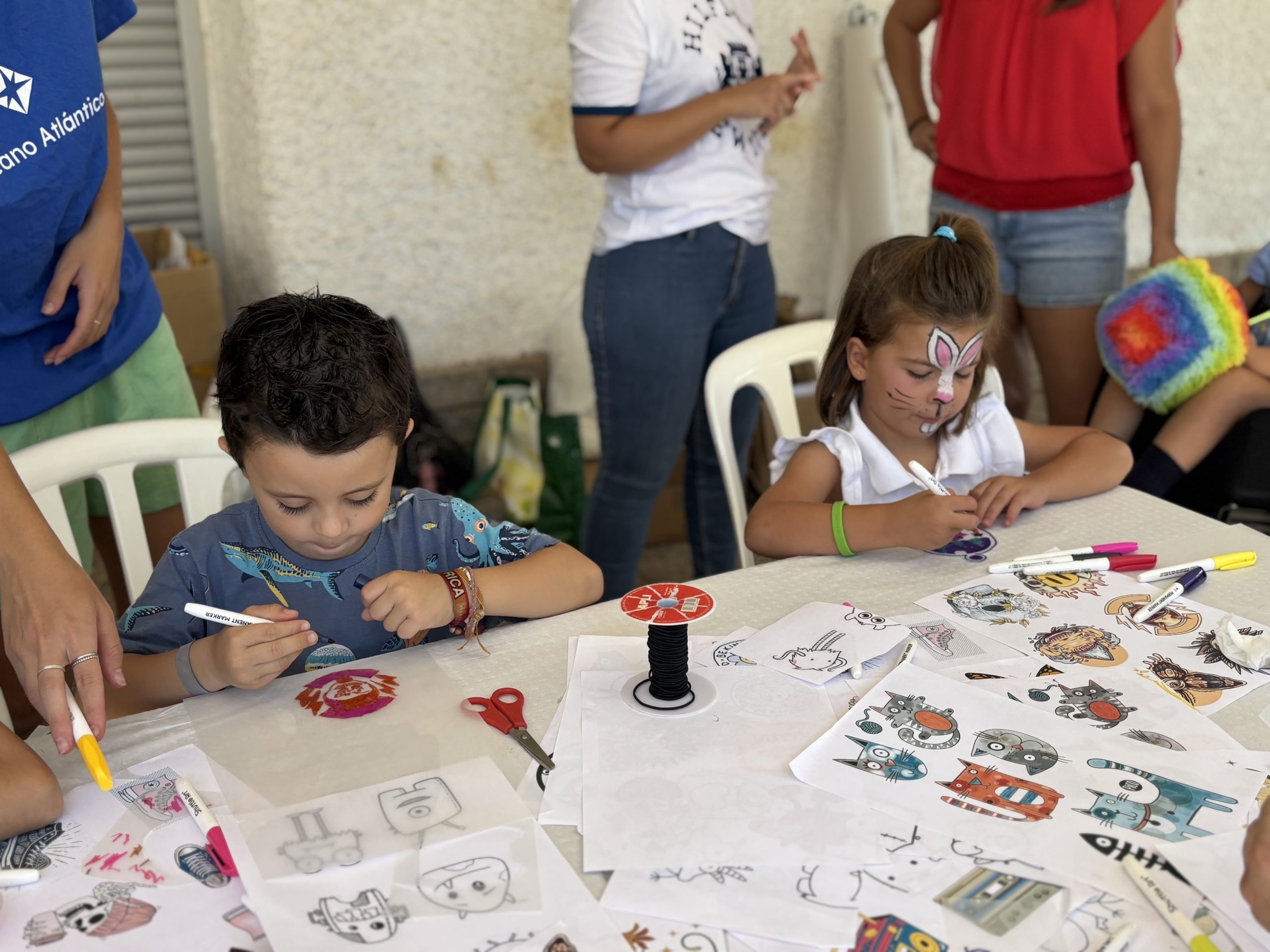 Durante la Jornada de Familias en Madrid, dos niños con pinturas faciales crean dibujos en mesa de manualidades