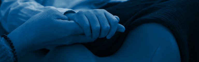 Primer plano de unas manos entrelazadas con ternura, descansando sobre una manta, transmiten el apoyo humano Fundación porqueViven