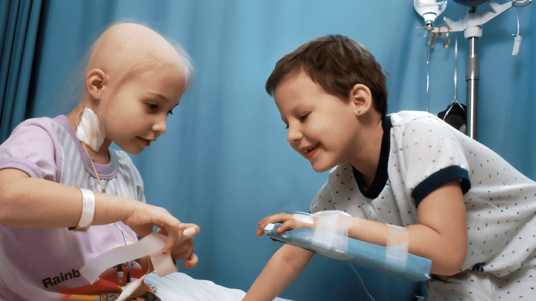 Dos niños en tratamiento interactúan animados en una sala hospitalaria; refleja la labor humana Fundación porqueViven
